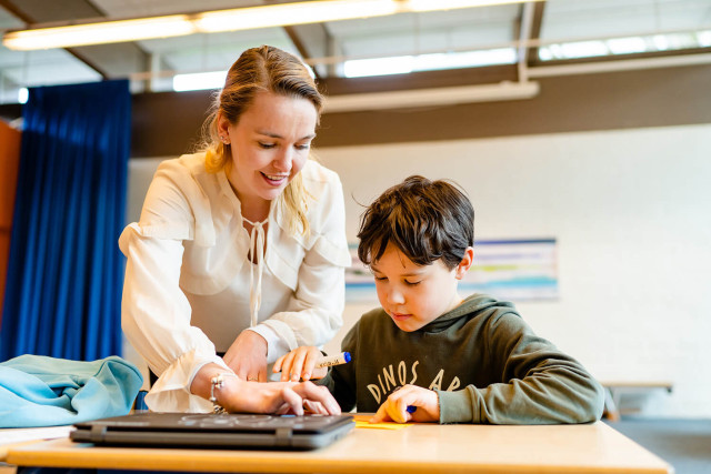 Leerkracht jongetje helpen met schoolwerk